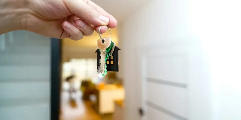 Close-up of a hand holding house keys, representing the home-buying process