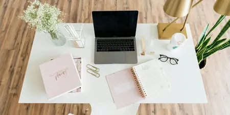 Bright home-office desk with a planner, keyboard, and writing space.