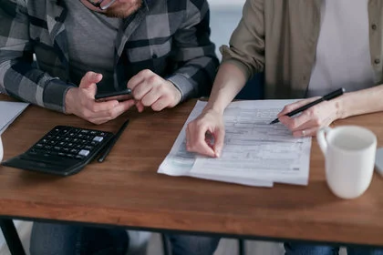 Couple filling out mortgage pre-approval application with calculator