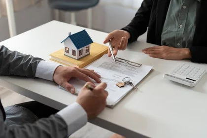 Mortgage advisor discussing refinance options with house model on desk